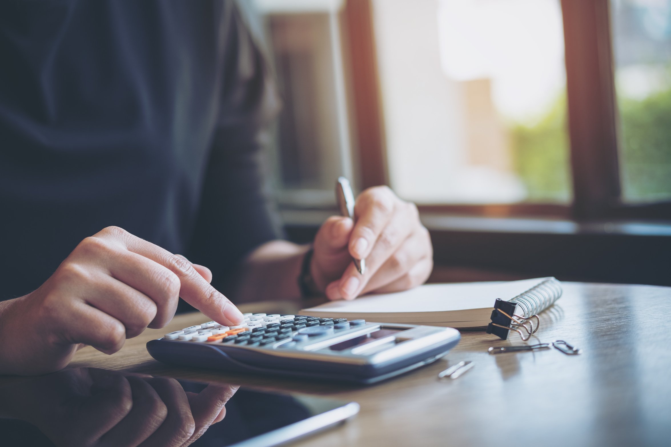 a business woman working , using calculator and writing on notebook